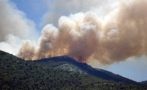 Al aire libre durante el día, una foto mirando el humo que se eleva de un incendio en una montaña