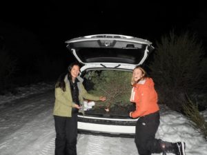 Lauren and Deborah pose in front of a car with it's hatchback open exposing a tree